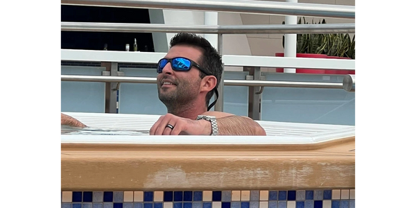Man relaxing in a hot tub, wearing blue reflective sunglasses.