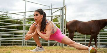 Woman stretching outdoors near a horse.