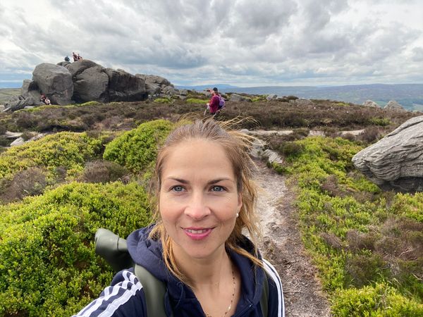 Woman hiking on a rocky trail with cloudy skies.