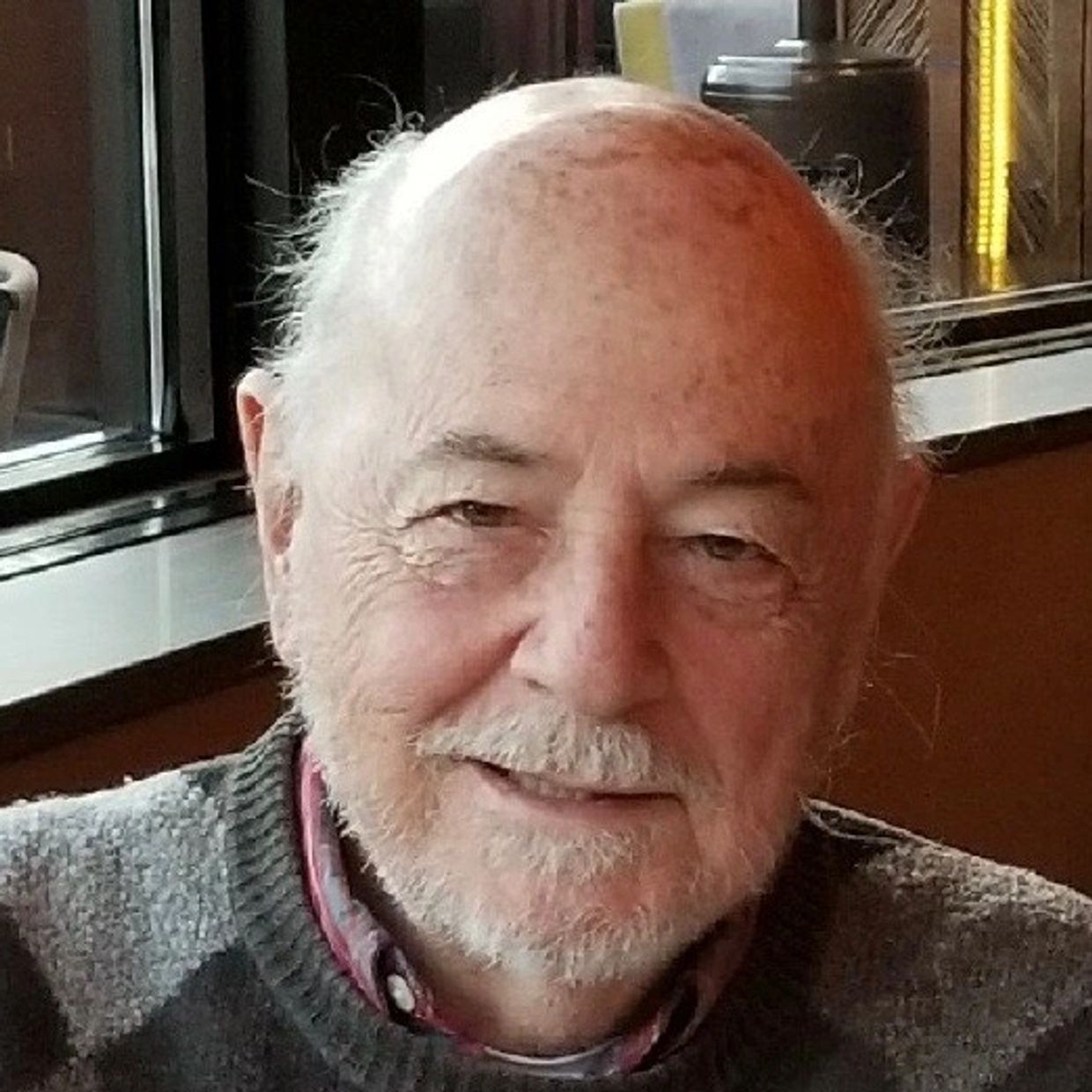 Smiling elderly man with white beard and mustache.
