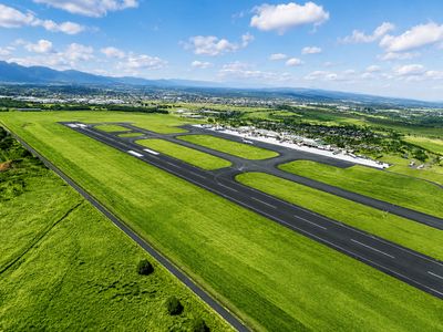 Aerial view of a green airport runway under a blue sky.