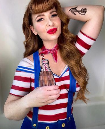 Woman dressed as a sailor with anchor tattoo and painted bottle.