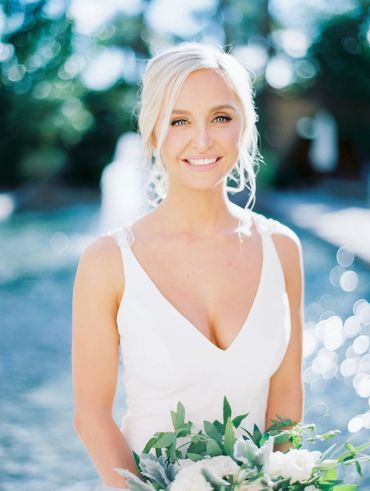 Smiling bride in white dress holding bouquet.