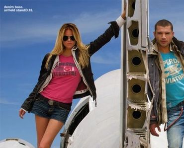 Two models posing by an aircraft at an airfield.