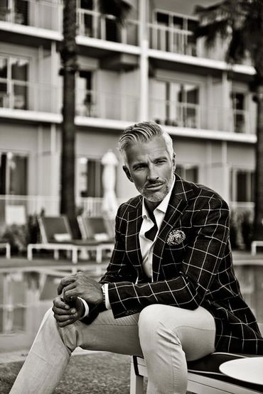 Stylish man in a checked blazer sitting by the pool.
