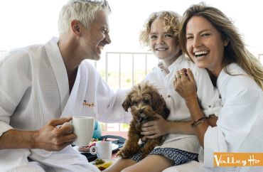 Happy family in robes with small dog relaxing together.