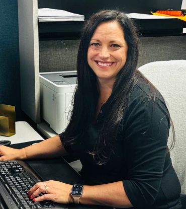 Smiling woman working at her office desk with a computer keyboard.
