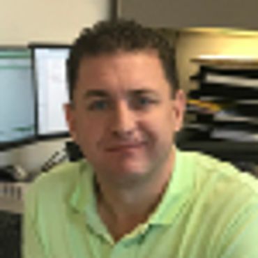Man in a green polo shirt sitting in an office.
