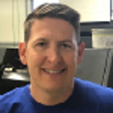 Smiling man in a blue shirt indoors.