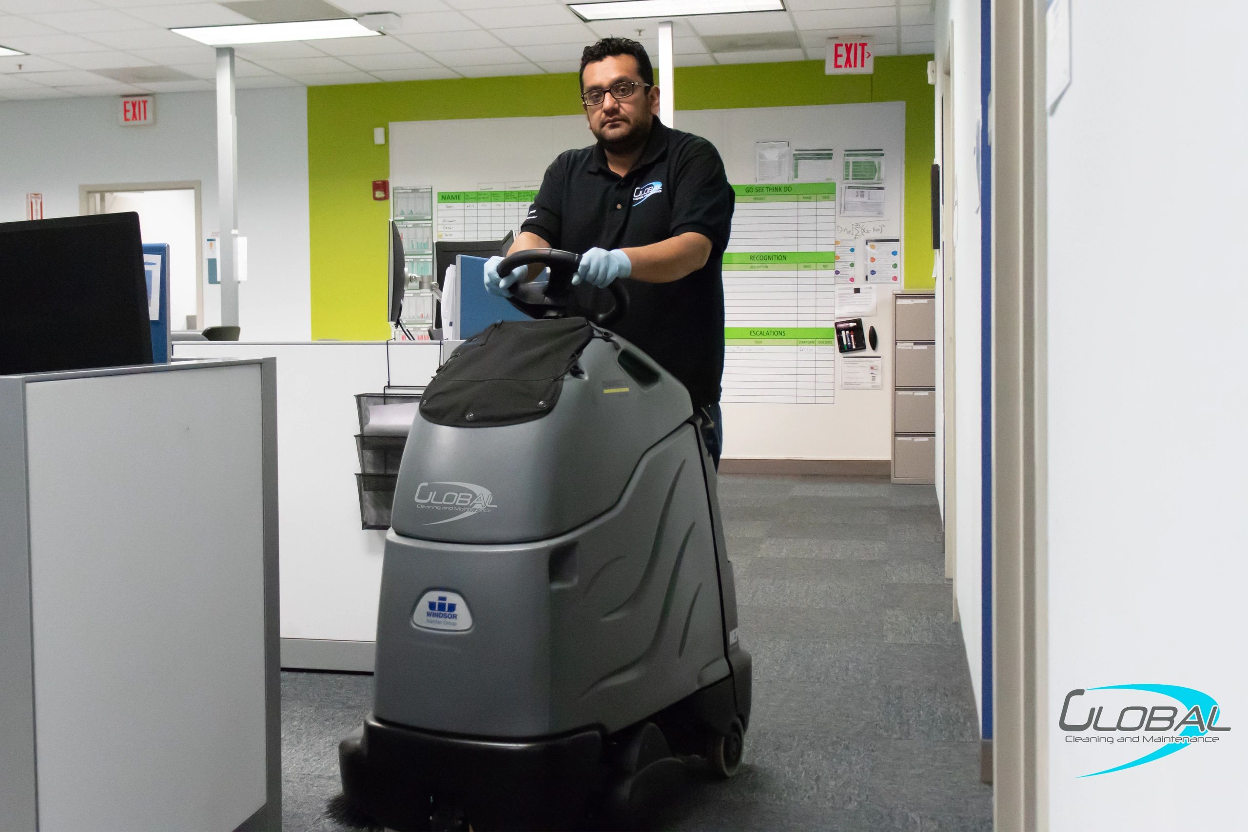 A man using a floor cleaning machine in an office.