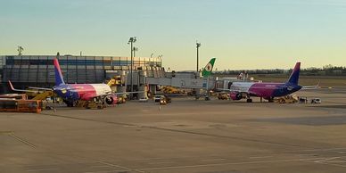 Two airplanes parked at airport gates during sunset.