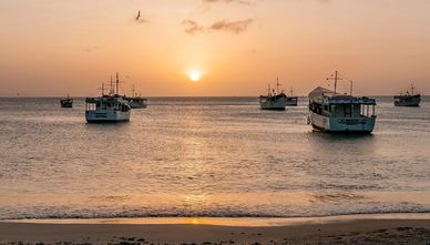 Fishing boats anchored during a serene sunset over calm waters.