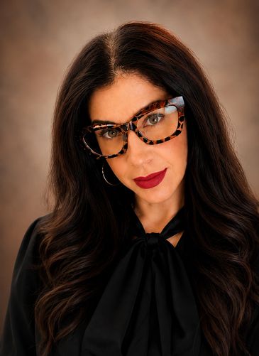 Woman with glasses and bold lipstick posing.