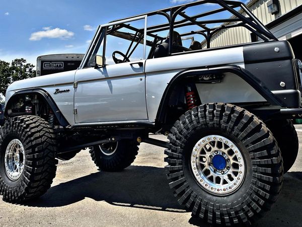 A lifted off-road Bronco with oversized tires and roll cage.
