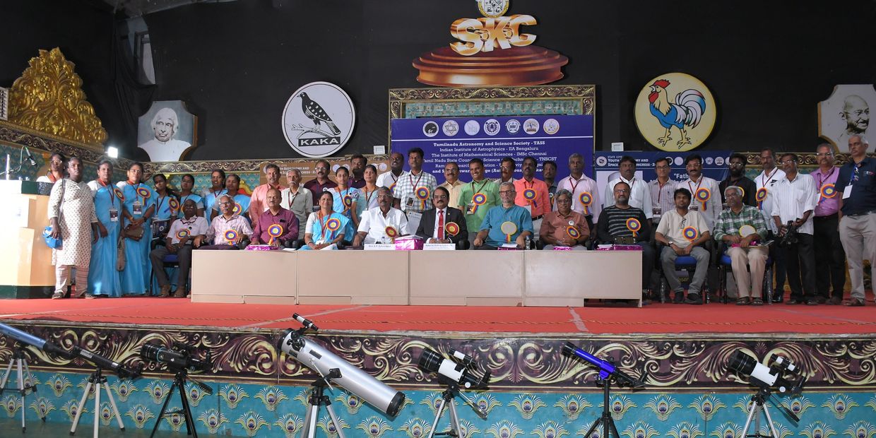 Group photo of astronomy society members with telescopes on stage.