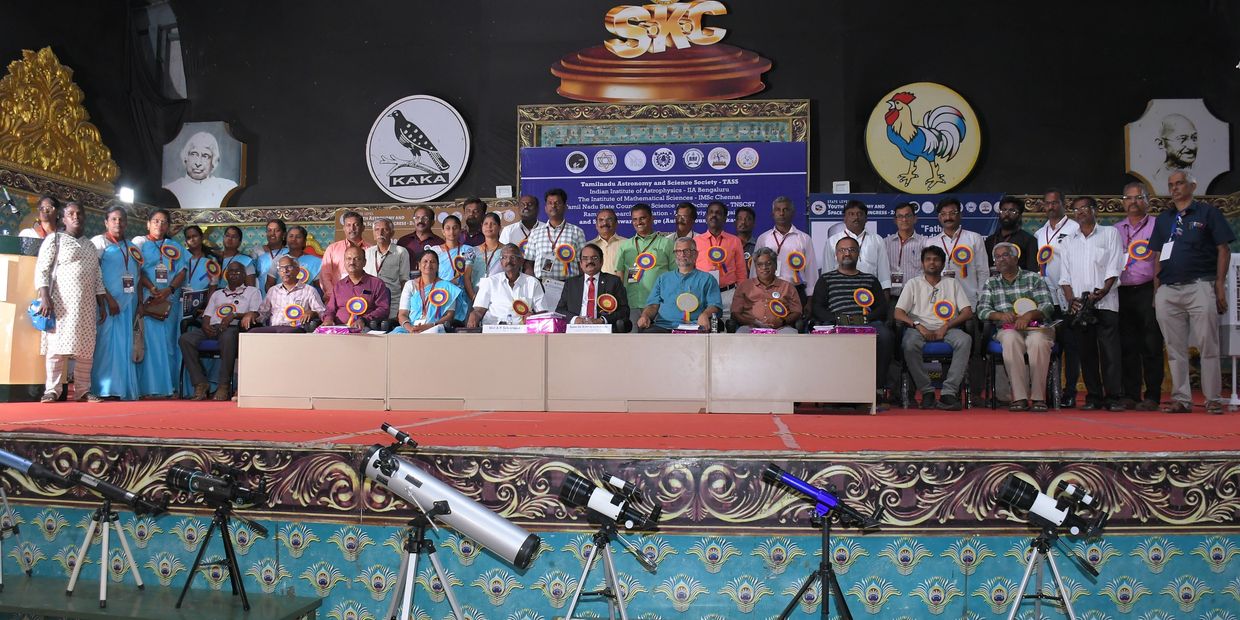 Group photo of astronomy society members with telescopes on stage.