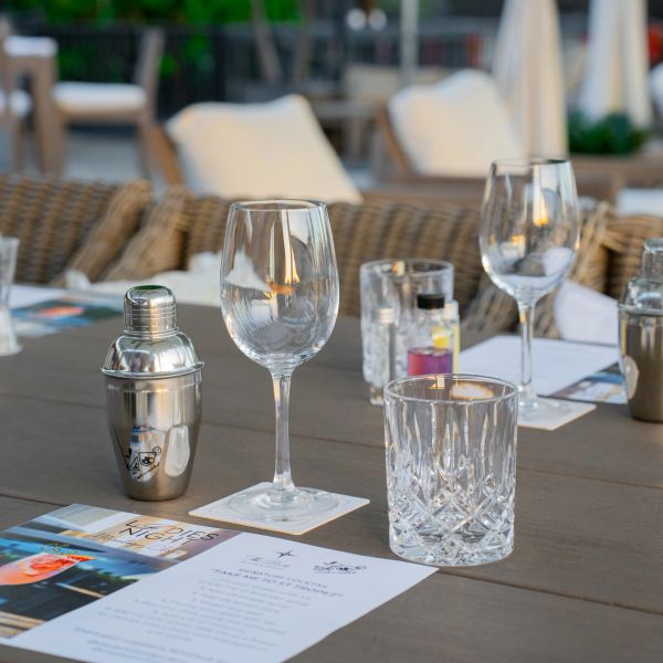 Table set with cocktail shaker, glassware, and menus for a cocktail night event.