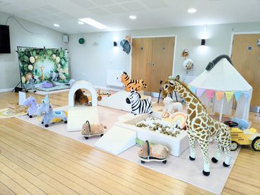 A bright, playful indoor kids' area with animal toys and soft play equipment.