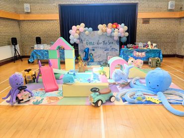 Colorful underwater-themed play area with toys and decorations for a child's first birthday.