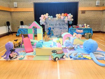 Colorful underwater-themed play area with toys and decorations for a child's first birthday.