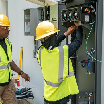 Electricians installing a panel for a standby generator in Naples home