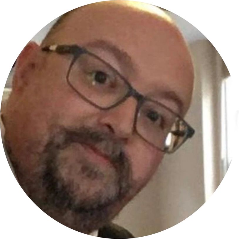 Close-up of a man with glasses, a beard, and a thoughtful expression.