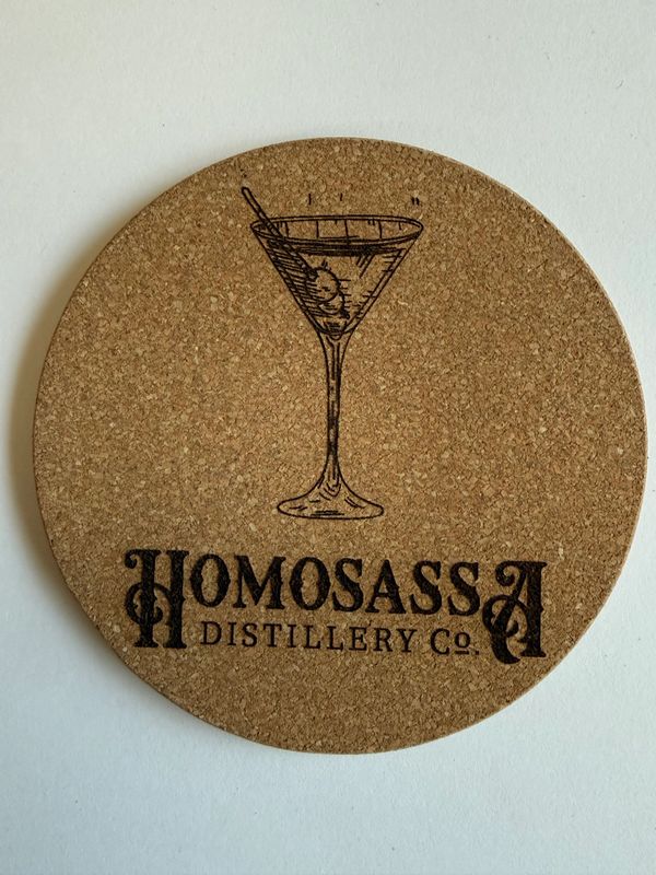 Round cork coaster with a cocktail glass and Homosassa Distillery Co logo.