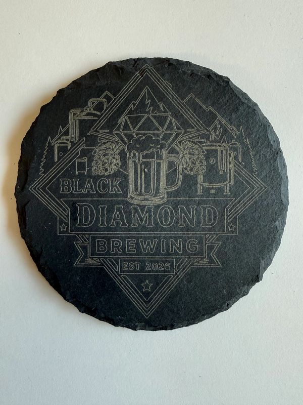 Black Diamond Brewing engraved on a round black slate coaster.