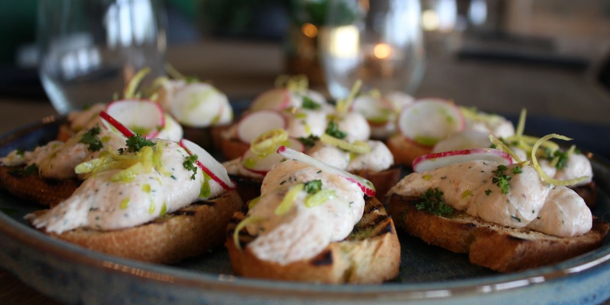 Grilled bread topped with creamy spread, radish slices, and herbs.