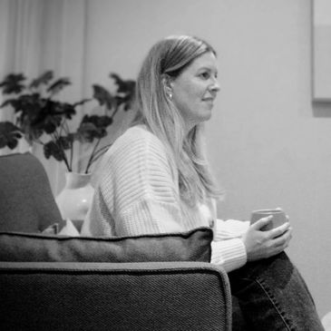 A counsellor sitting in a calm, inviting environment holding a coffee cup