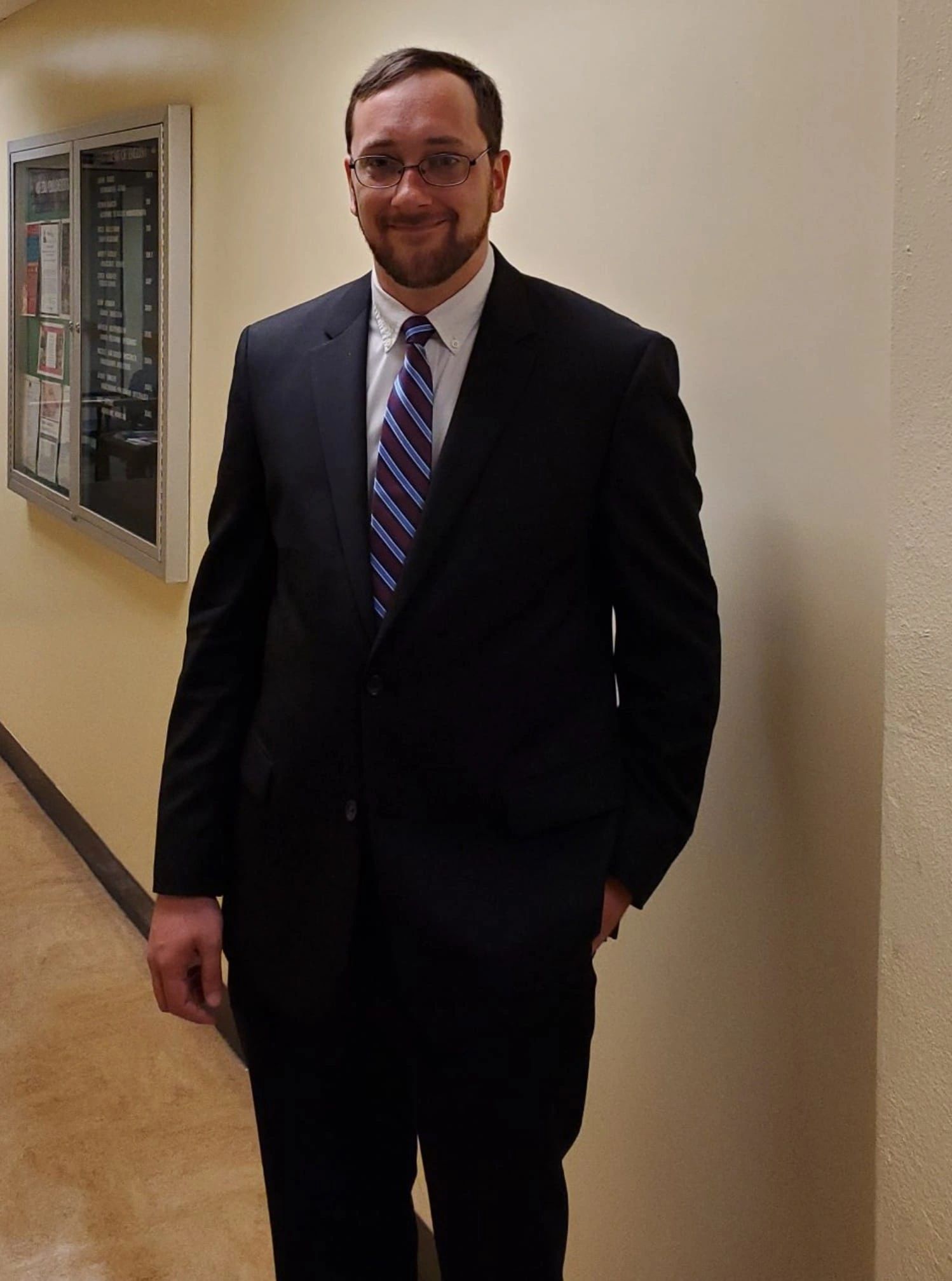 Image shows Dr. Rea standing in a hallway in a suit and tie.