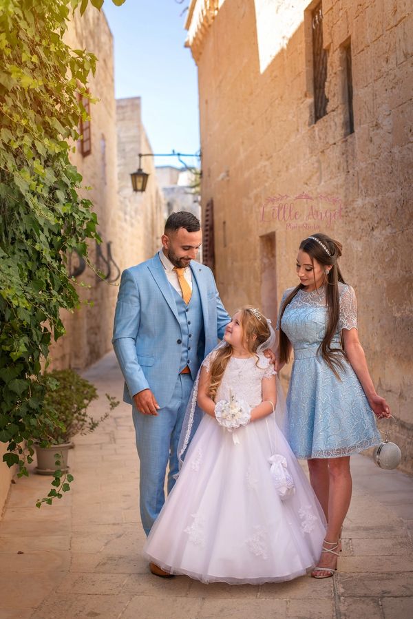 A family dressed elegantly poses in a charming stone alleyway.