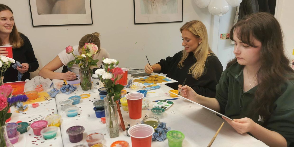 group of people sitting together and doing oil painting