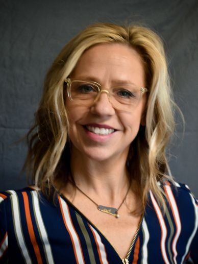 Smiling woman with glasses and blonde hair.