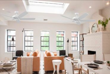 Bright living room with orange sofas and skylight.