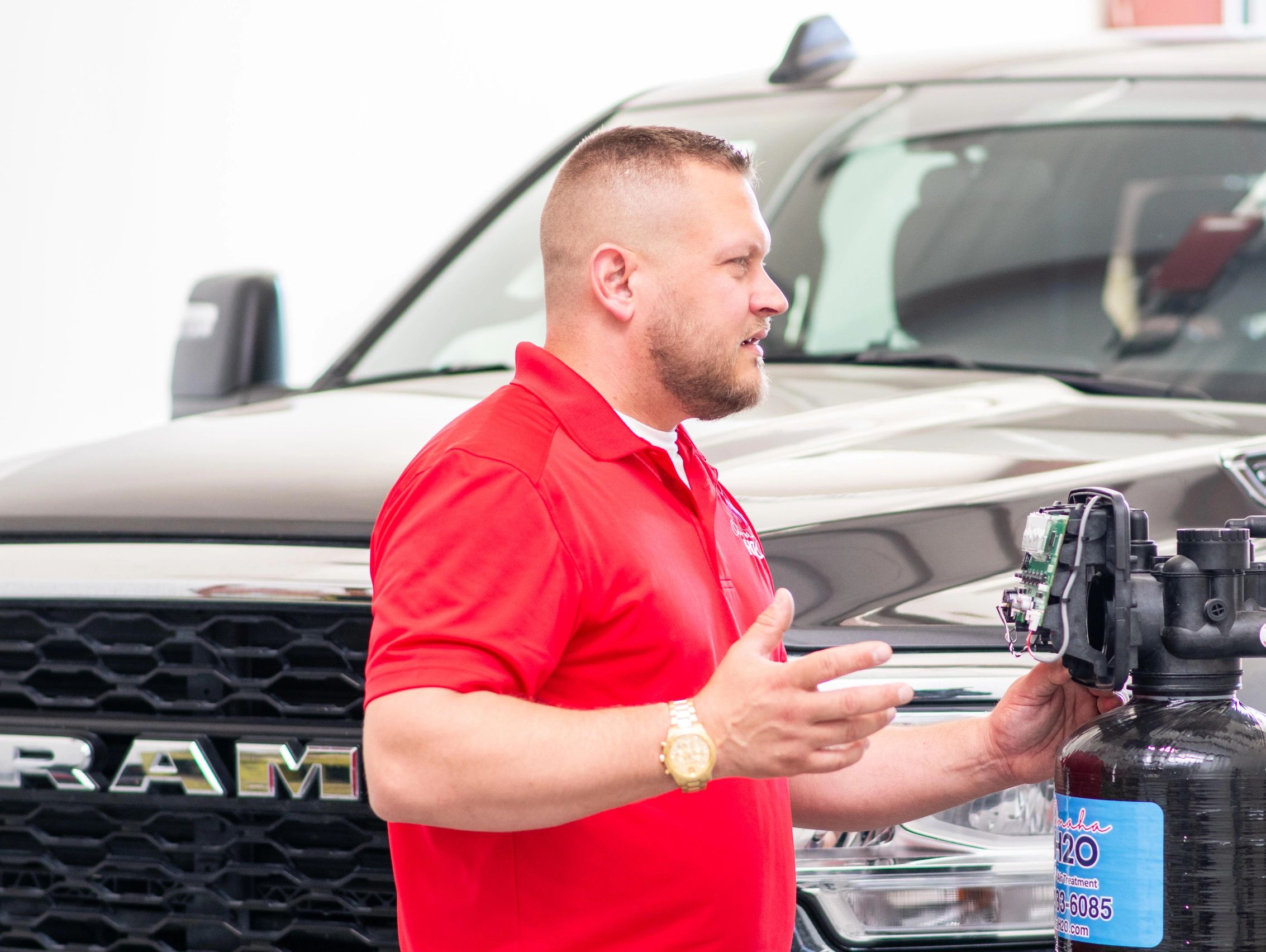 Man in red shirt explaining water filtration system in front of a RAM truck.