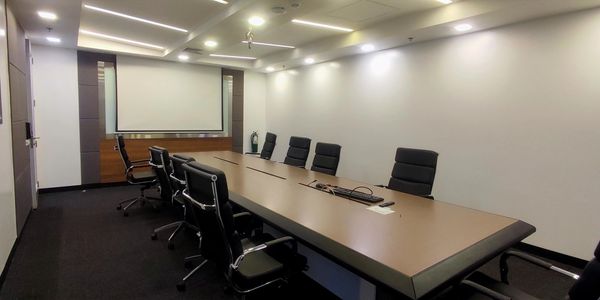 Modern conference room with a large table and black chairs.