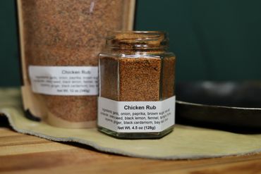 Jar of spices on butcher block table next to cast iron pan on leather swatch.