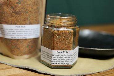 Jar of spices on butcher block table next to cast iron pan on leather swatch.