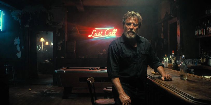 Man sits at a bar with a neon "Last Call" sign glowing behind him.