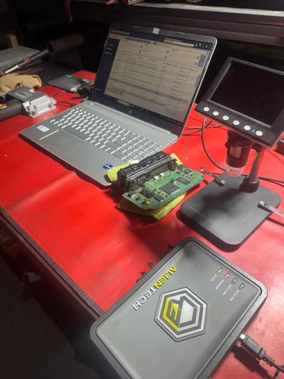 Electronics repair setup with laptop and diagnostic tools.