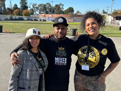 Three people posing outdoors with smiles and casual attire.