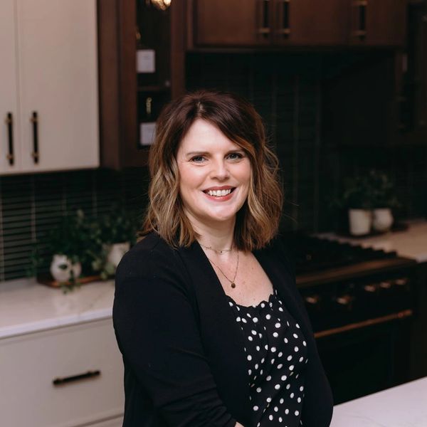 Smiling woman with shoulder-length hair in a modern kitchen.