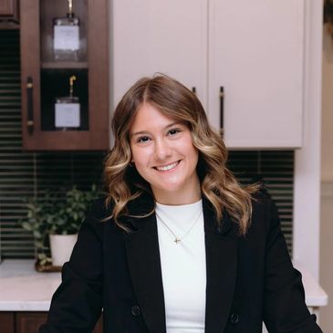 Young woman with wavy hair smiling in a kitchen setting.
