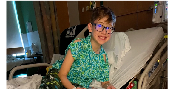Givelist® Wish List Creator Dominic, 11 year old boy fighting Leukemia, is in a hospital bed smiling