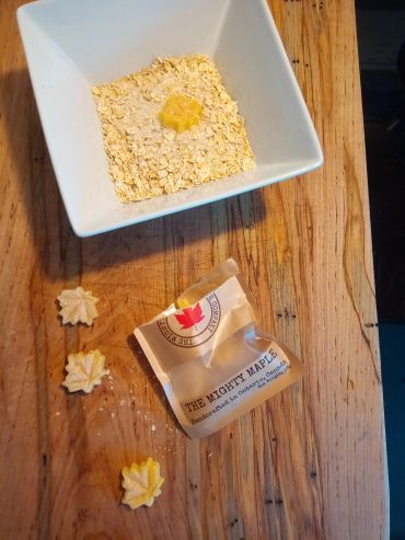 A bowl of oats with butter and maple cookies on a wooden table.