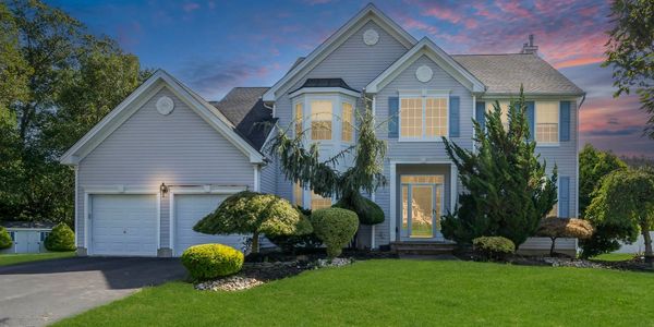 Two-story house with well-manicured lawn and evening sky.