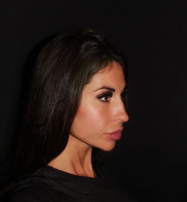 Profile portrait of a woman with long dark hair against a black background.