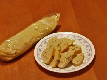 Sliced homemade bread on a plate with a loaf wrapped in plastic.