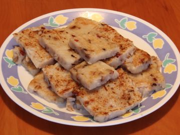 Plate of pan-fried radish cakes on a floral plate.